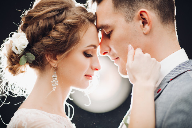 gorgeous-bride-handsome-groom-touching-by-faces-each-other_132075-2277